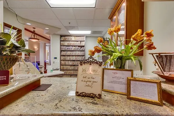 The front desk at Dr. Sabourin's La Jolla office, with a welcome sign, flowers and cherry wood