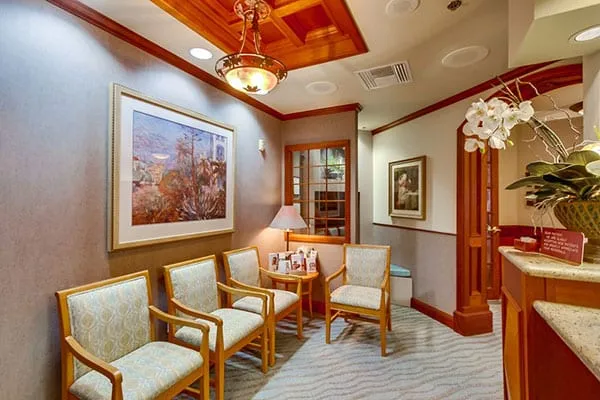 The waiting room, with upholstered chairs, a chandelier and framed art